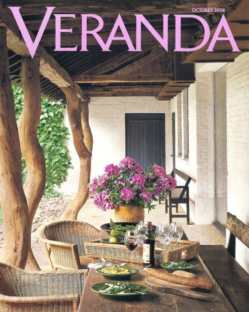 Veranda magazine cover with outdoor patio area with rustic beams, clay walls, and potted pink flowers.